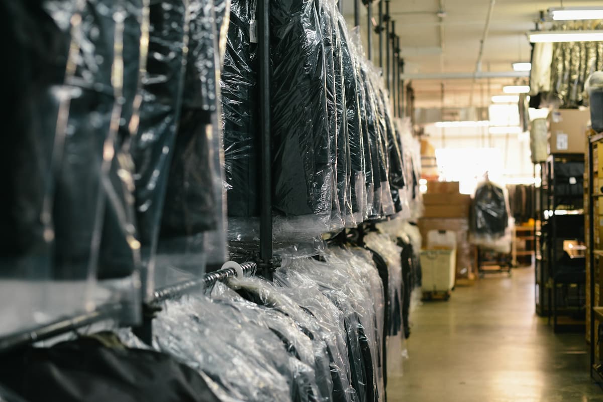 Suits in clear plastic bags along a rail